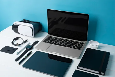 Poze cu mai multe aparate electronice precum laptop tableta smartwatch telefon si ochelari vr asejate pe o masa