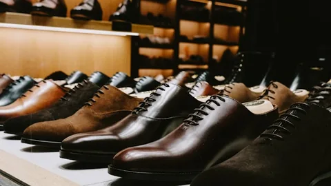 Poza cu mai multe perechi de pantofi eleganti din piele naturala de diferite culori asejate pe rafturi intr-un magazin special de pantofi