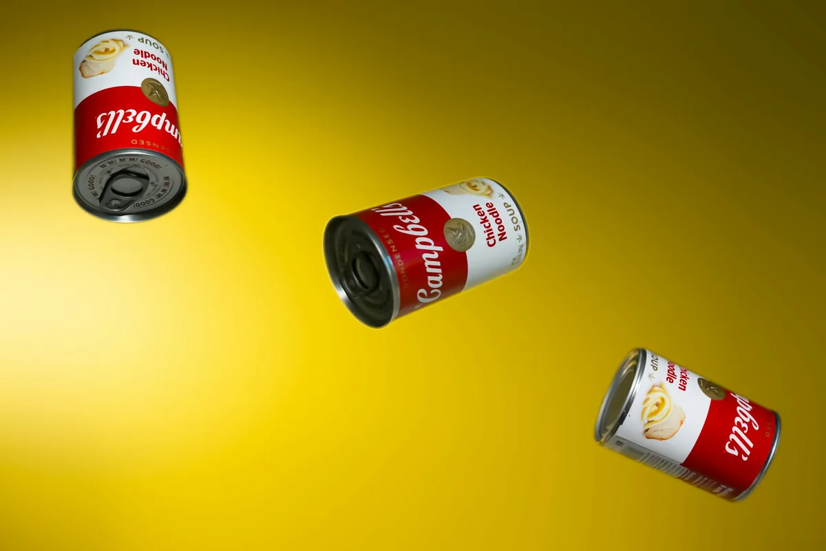 Poza cu mai multe conserve in aer pe fundal galben