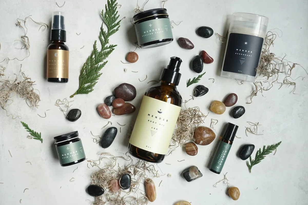 Poza cu mai multe produse cosmetice asejate frumos cu pietricele decorative intre ele si o frunza de brad